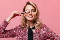 portrait-woman-with-wavy-hair-covering-her-eye-with-makeup-brush